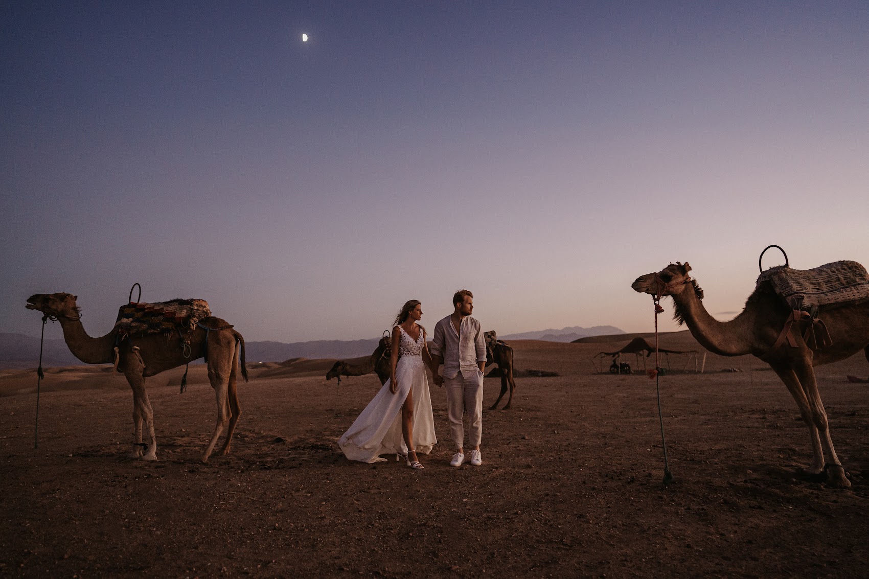 Couple in the Agafay desert with camels at twilight
